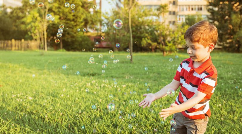 Happy boy playing with soap bubbles in the park