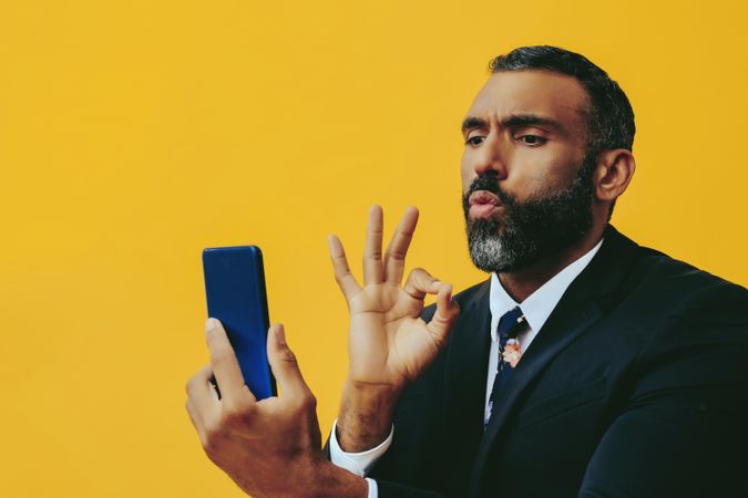 Intense Black businessman in suit gesturing at smartphone screen