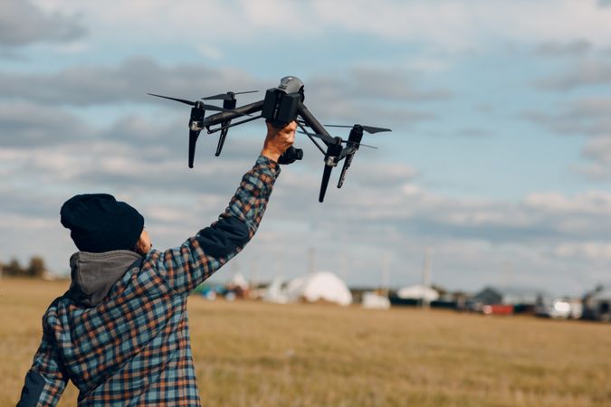 Back view of man in plaid shirt holding a drone