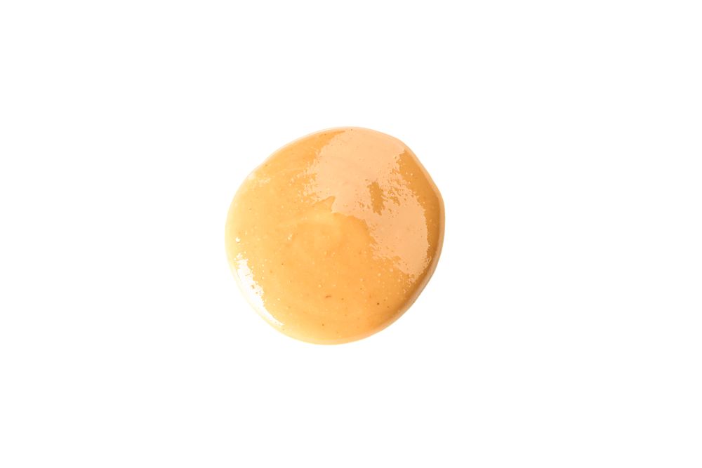 Creamy peanut butter isolated on light background, top view. A traditional product of American cuisine