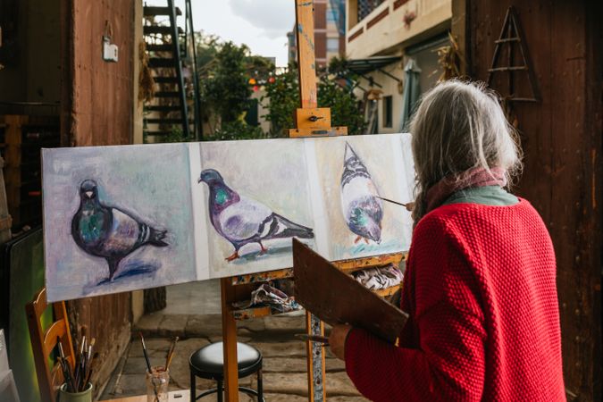 Anonymous mature woman painting on canvas in garden