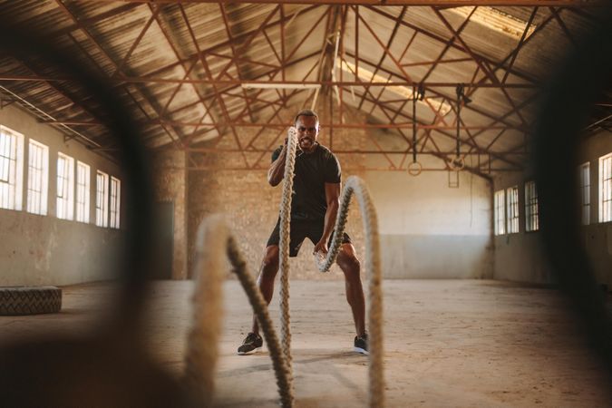 Tough man working out in cross training gym made inside old factory