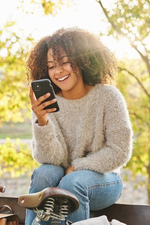Delighted Black woman using cellphone in park