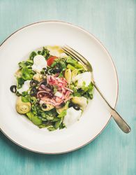 Artichoke salad, on light blue background, vertical composition