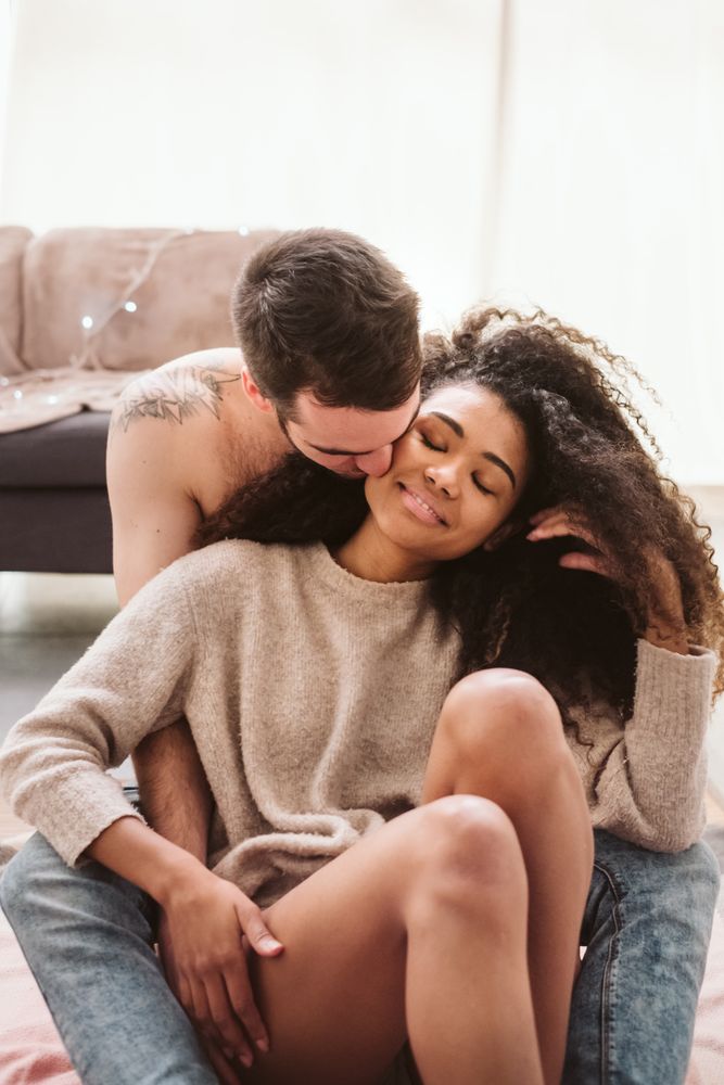Multiethnic couple hugging on floor at home