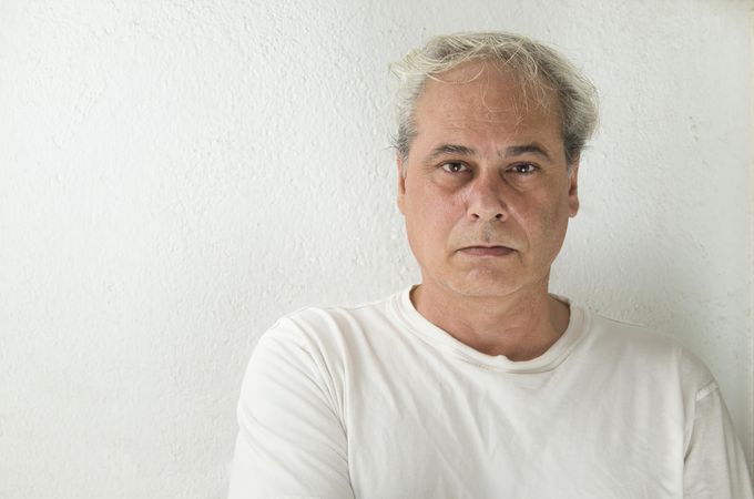 Portrait of disappointed middle aged man in light shirt against light wall
