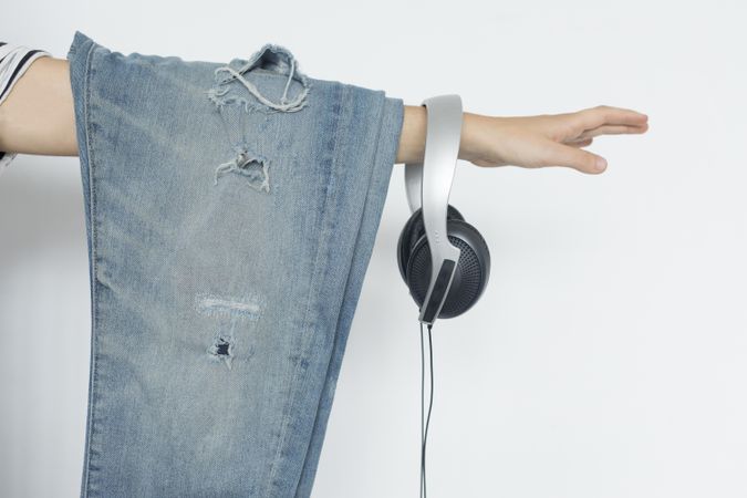 Jeans and headphones hanging off outstretched arm