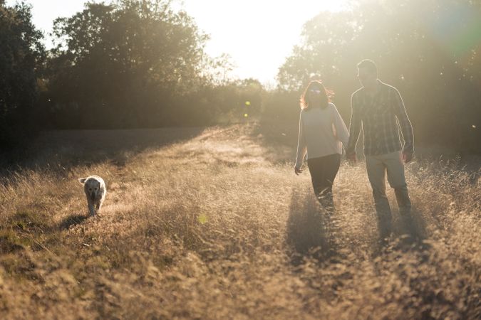 Couple with dog in countryside at sunset