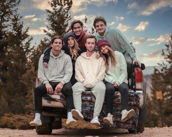 Group of young people sitting on a car in nature