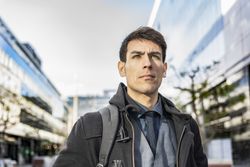 Low-angle view of an businessman with his backpack on looking away while walking from his office