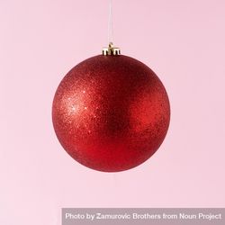 Red glitter Christmas bauble on pastel pinks background 48gpv5