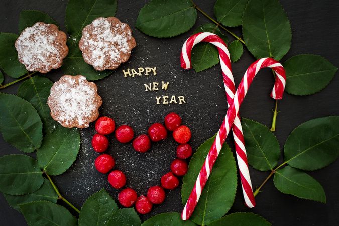 inscription of new year on a board with cupcakes and candy red