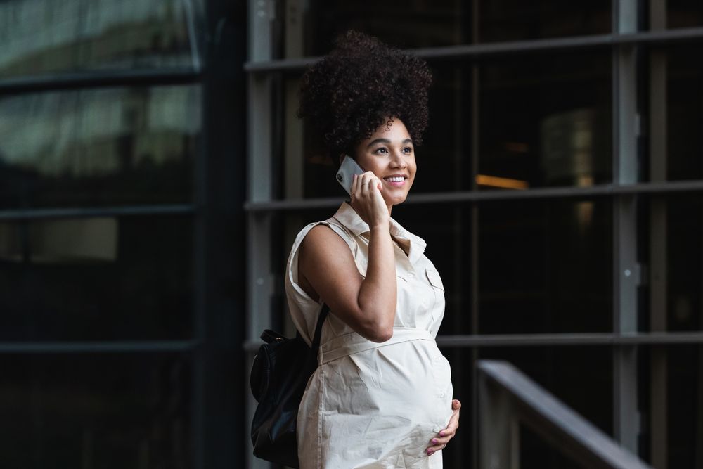 Smiling Black pregnant woman talking on smartphone