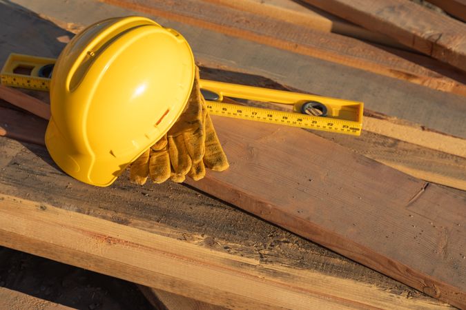 Abstract of Constrcution Hard Hat, Gloves and Level Resting on Wood Planks