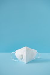 Medical mask on pastel blue background
