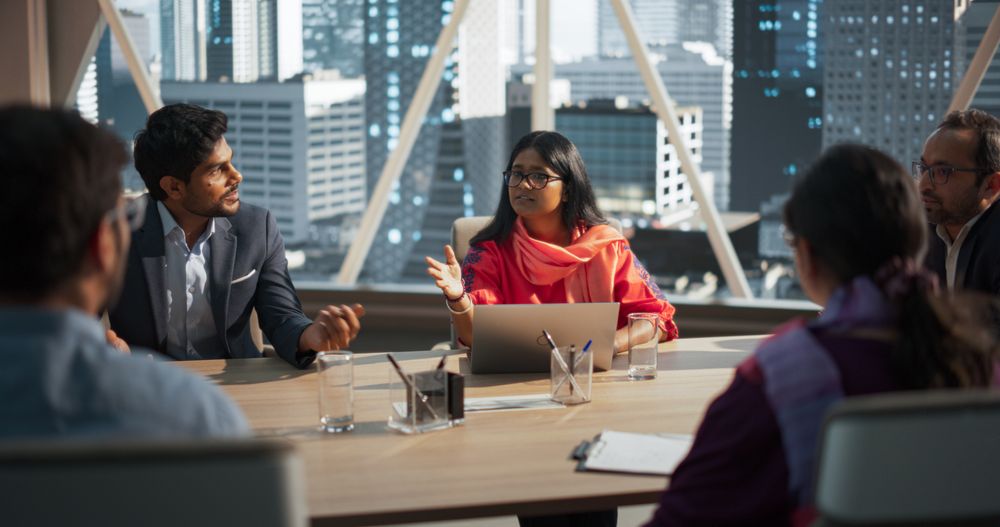 South Asian Colleagues Gathered Around a Conference Table, Talking.