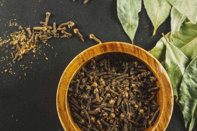 Bay leaves near bowl with cloves