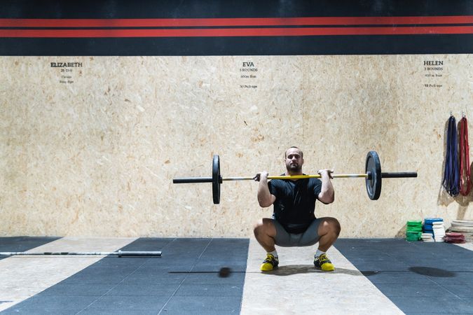 Muscular sportsman lifting heavy barbell