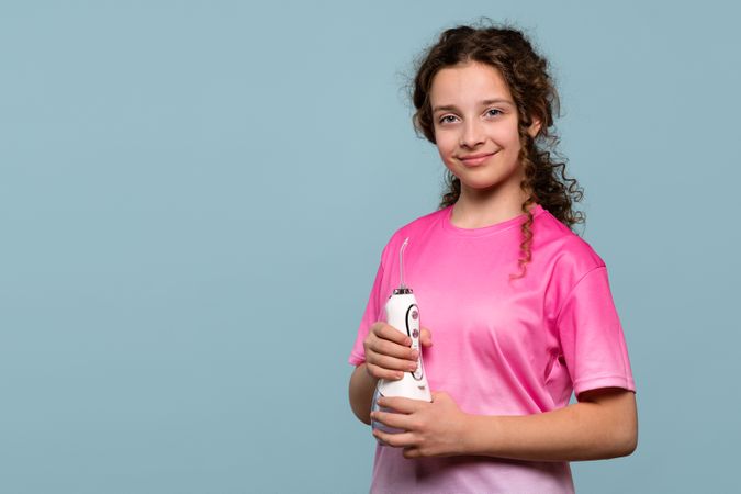 Girl in pink shirt holding oral irrigator