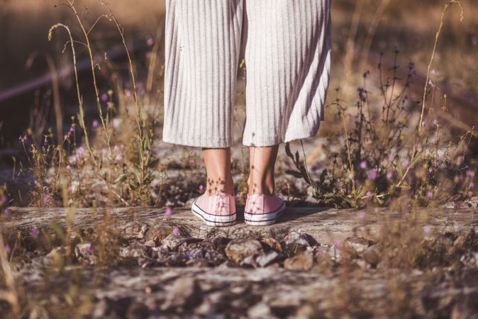 Long haired woman standing on railways overgrown with dry grass