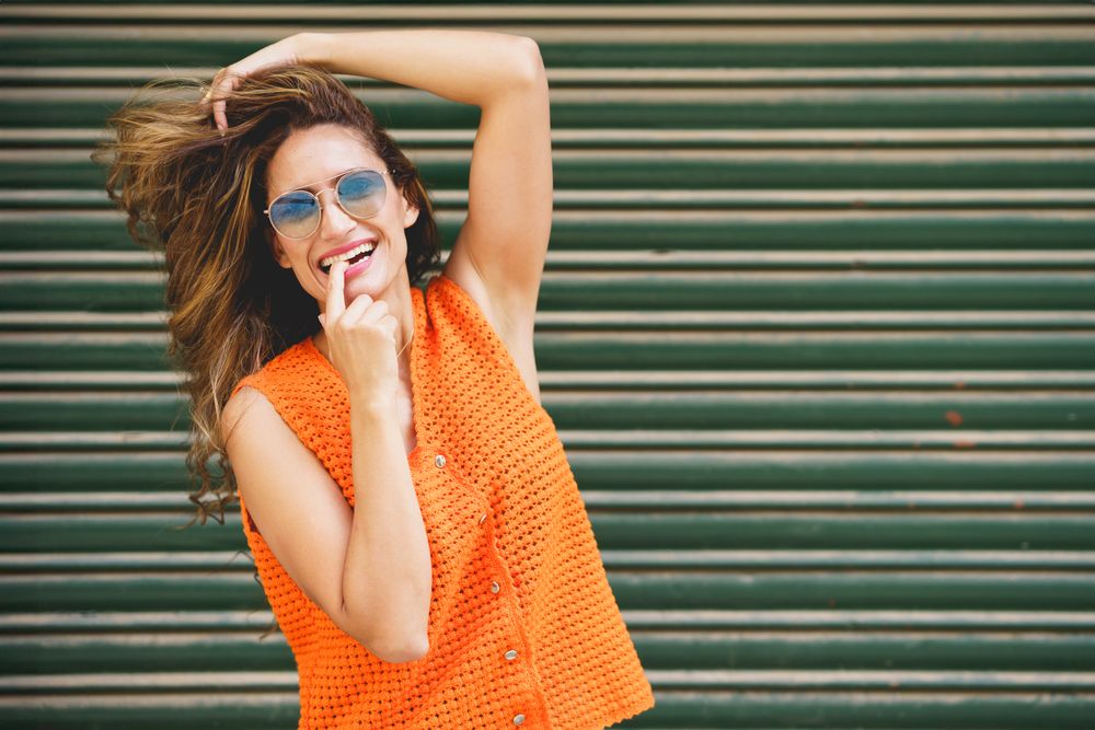 Carefree woman with hand to her mouth outside