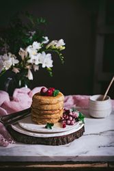 Pile of raspberry pancakes with honey on plate