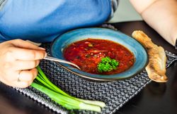Person eating red Ukrainian borscht