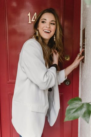 Stylish woman standing near red door