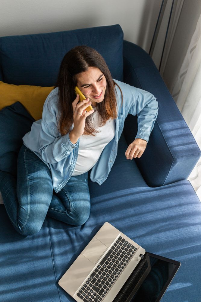 Pregnant woman talking on smartphone during remote work