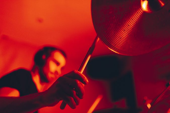 Man with drumsticks playing on drums in redness