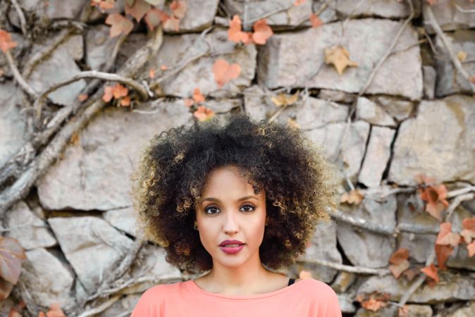 Portrait of beautiful Black woman with afro hairstyle in front of stone wall