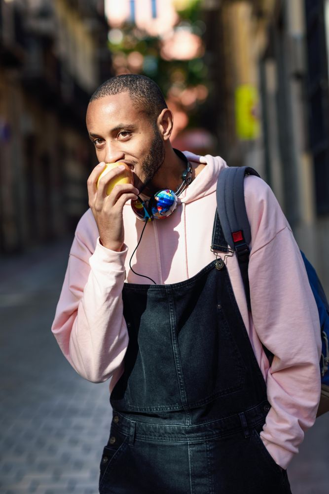 Vertical shot of male on European street biting an apple