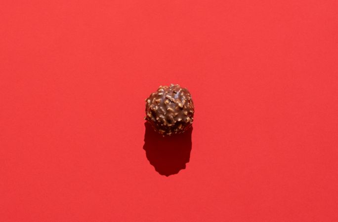 Chocolate truffle minimalist on a red background in bright light