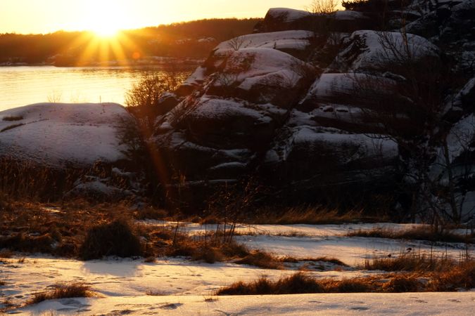 Rocky peaceful shore with snow crust in sunrays