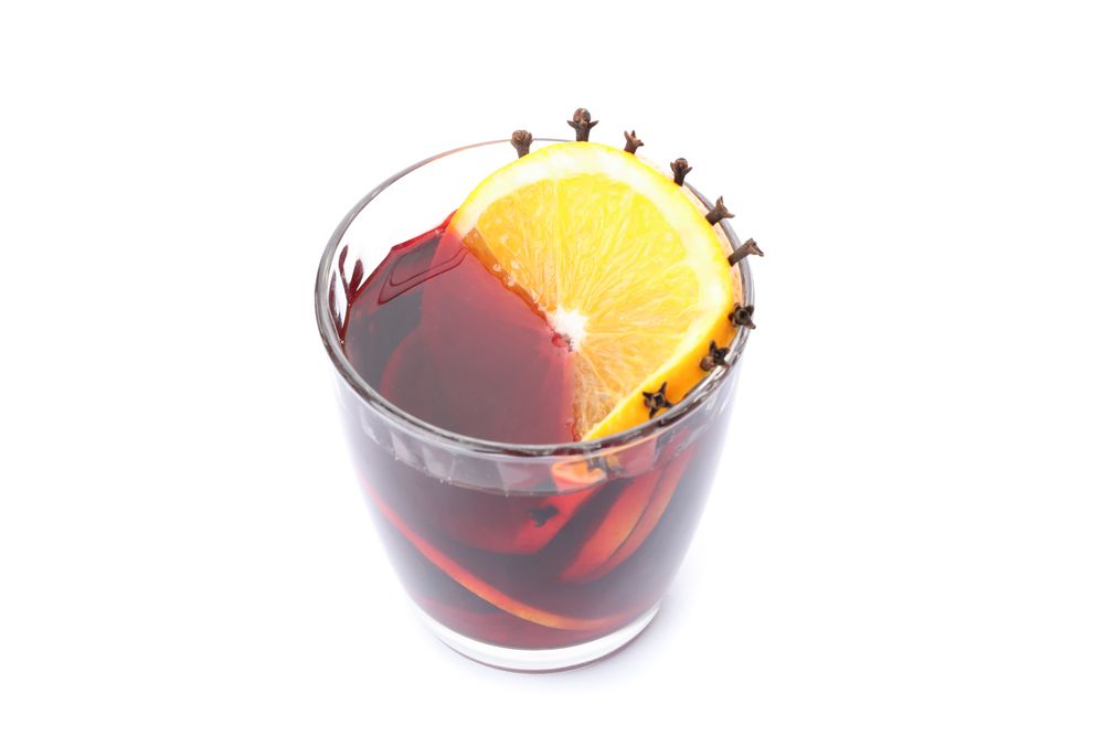Glass of tasty mulled wine with orange isolated on studio background