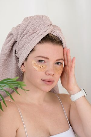 Applying eye patches in skincare routine.