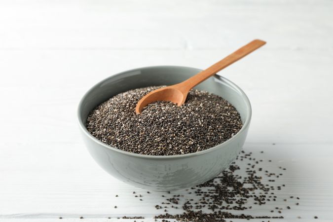 Chia seeds, wood spoon and bowl on wooden background, copy space