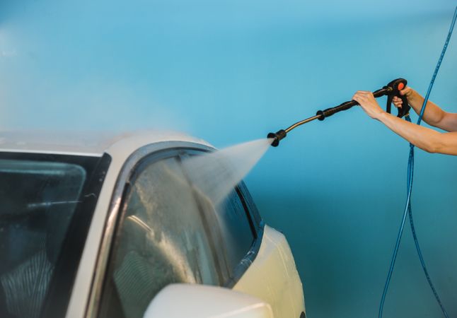 Crop woman washing windows of car