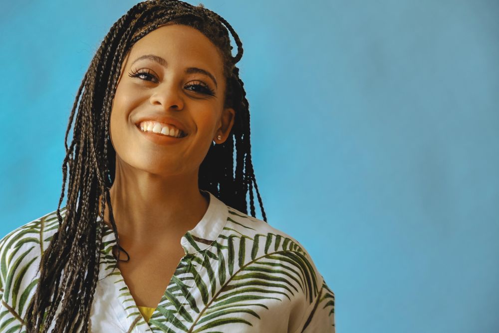 Portrait of confident happy female with long braided hair in printed leaf shirt, copy space