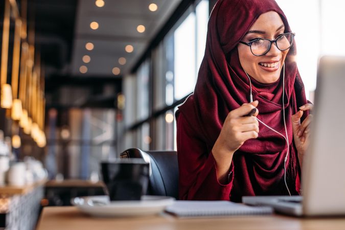 Smiling Muslim woman having a video chat on laptop at coffee shop