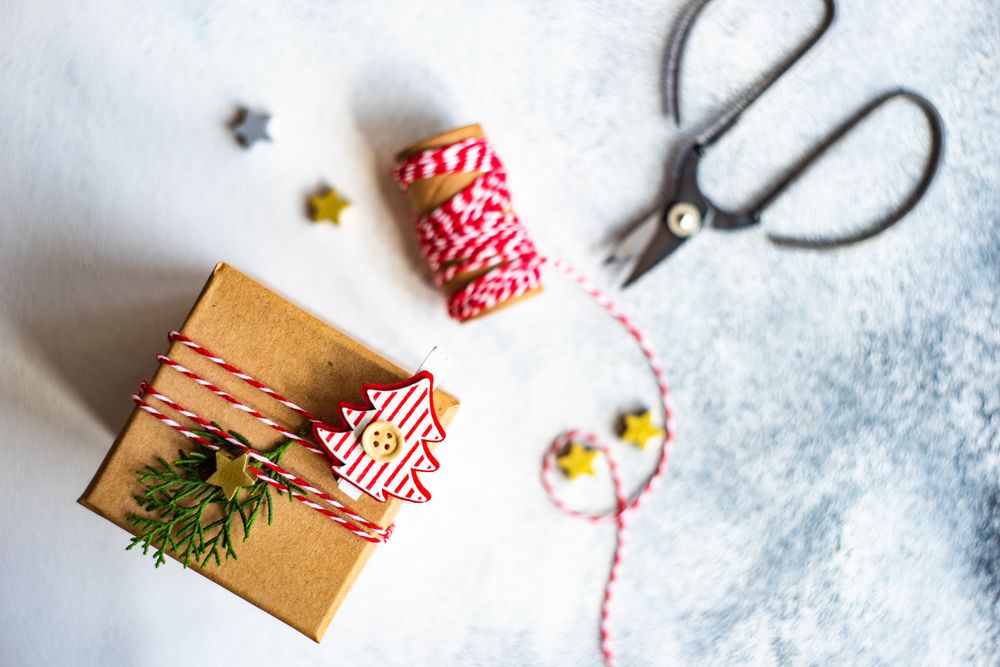 Top view of brown Christmas present with tree decorations, scissors and string