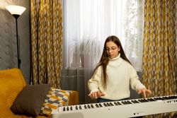 Young girl practicing piano in well-lit room with cozy decor.