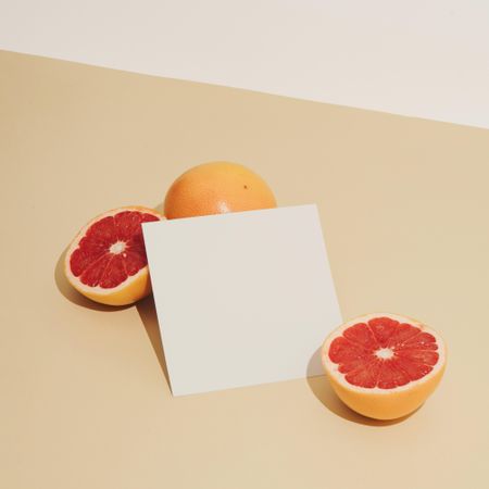 Grapefruit halved with paper card on beige background