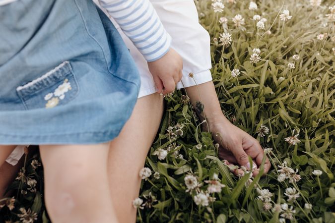 Crop mother and daughter sitting on grass