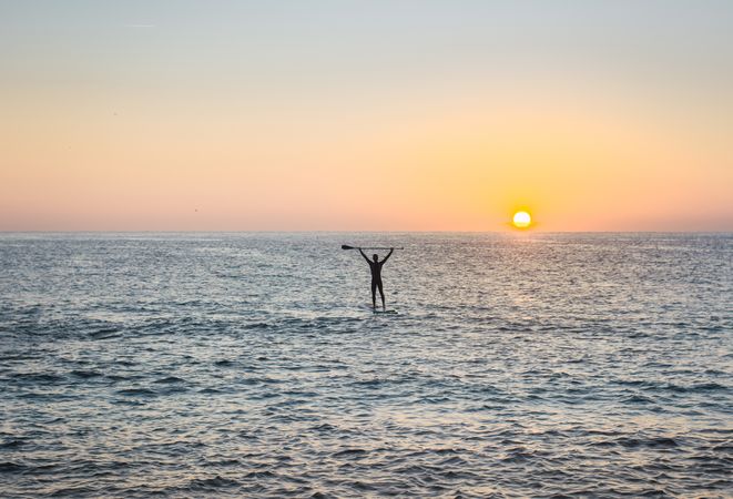 Man practicing paddle surfing with neoprene in a sunrise