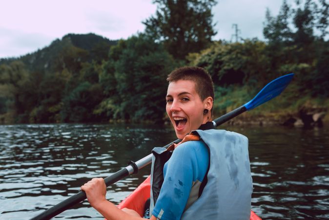 Female kayaking with paddle in raised hands