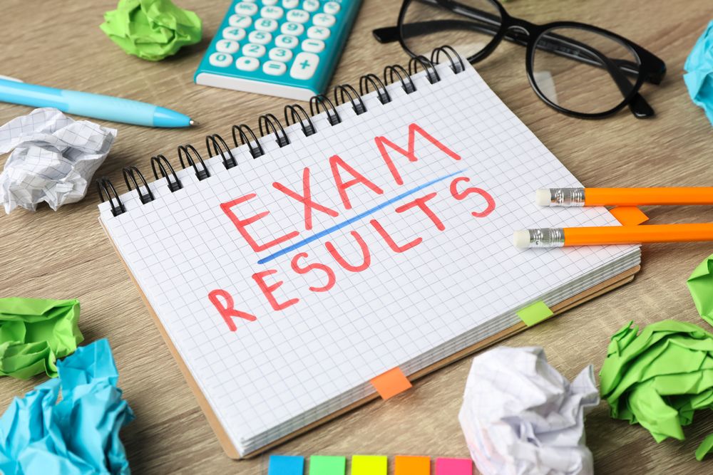 Open notebook with the word “exam results” with glasses and stationary