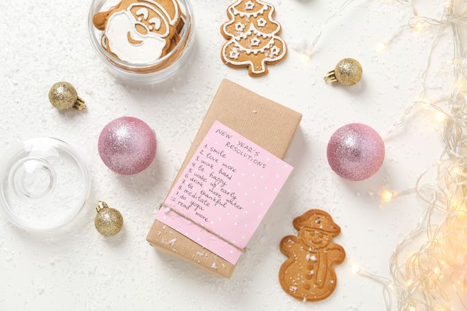Cookies and paper with list on box on plain background, top view