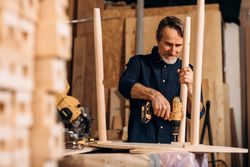 Man drilling screws into table in shop