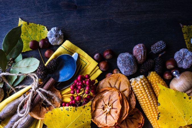 Seasonal autumn flatlay with nuts, berries, vegetable and fruits on dark wooden background with copy space